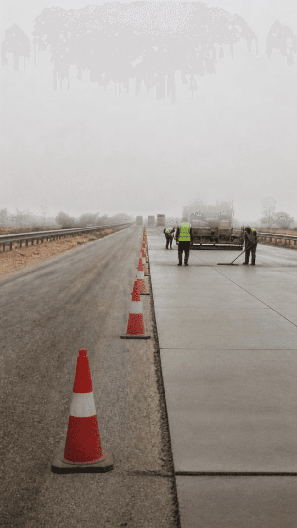 A maintenance crew working behind a line of cones on one carriageway, fresh pavement meeting older surface.