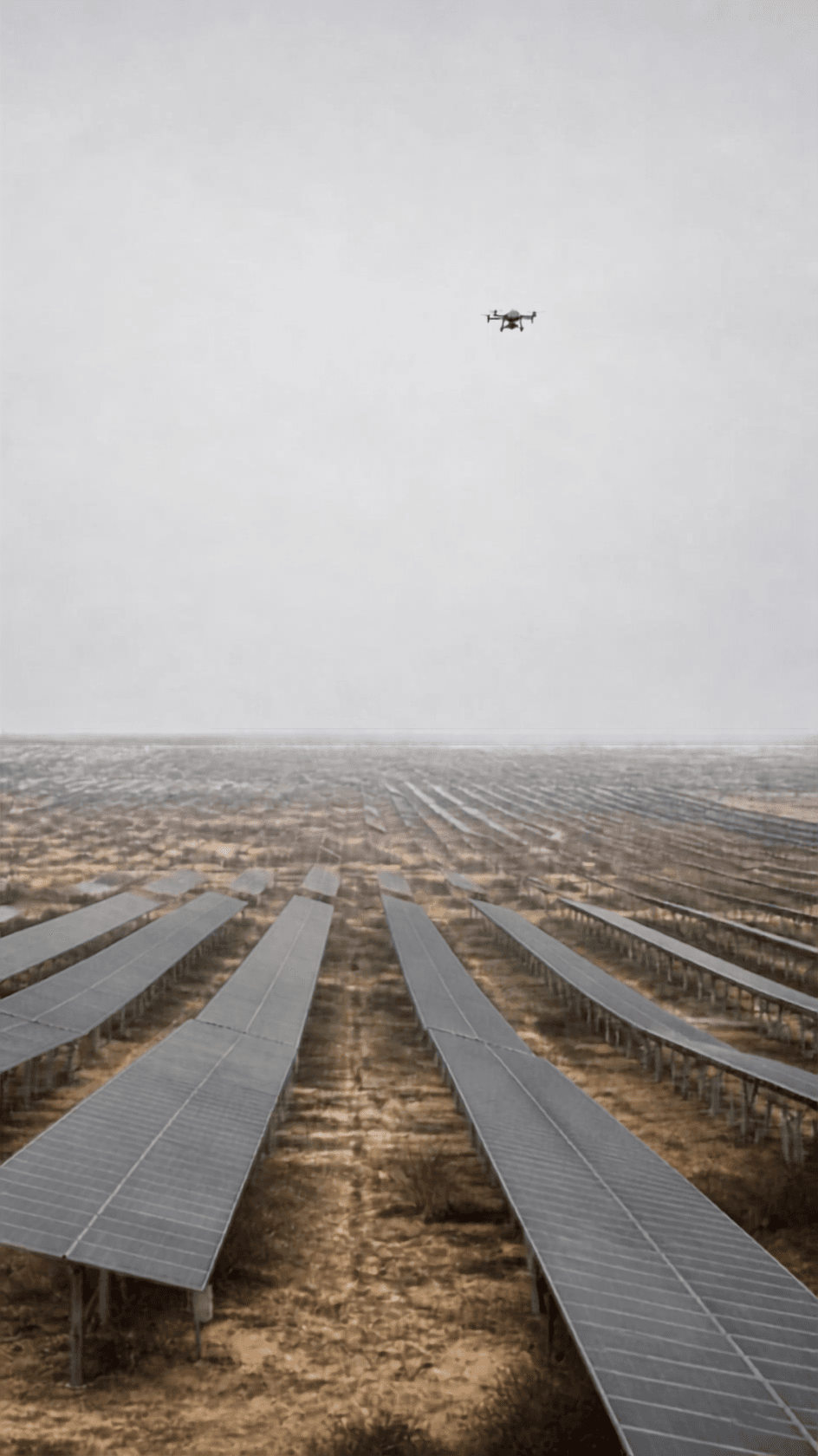 Rows of solar panels receding across flat arid ground, a survey drone overhead.