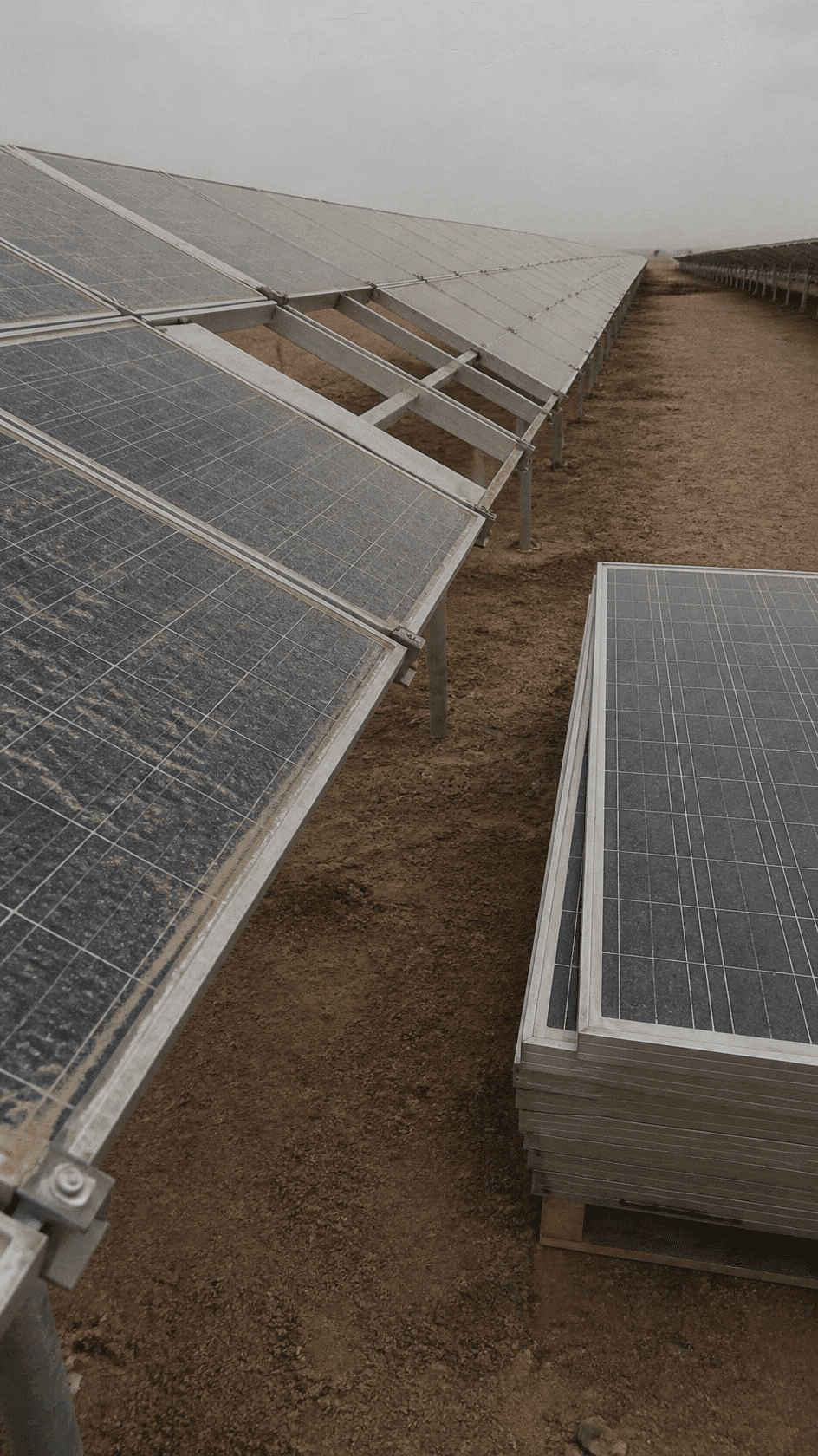 Weathered solar modules on their mounting rails with replacement panels stacked alongside.