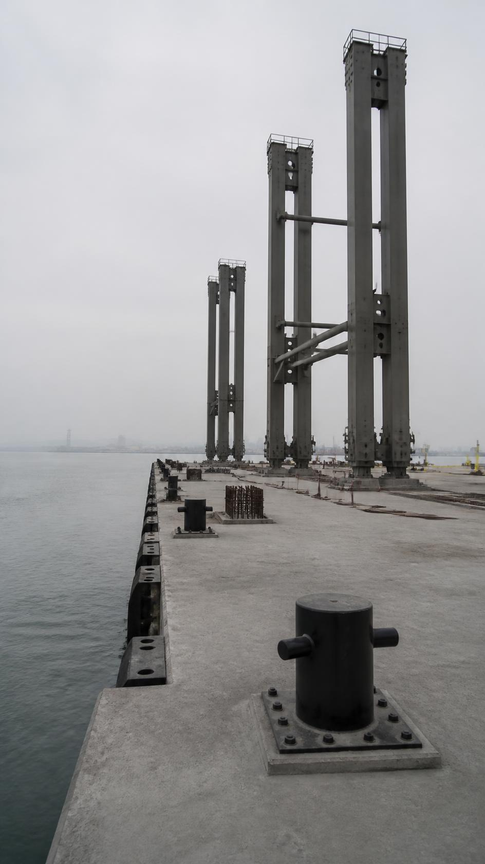 A container quay under construction, crane legs partly erected on a new concrete deck.