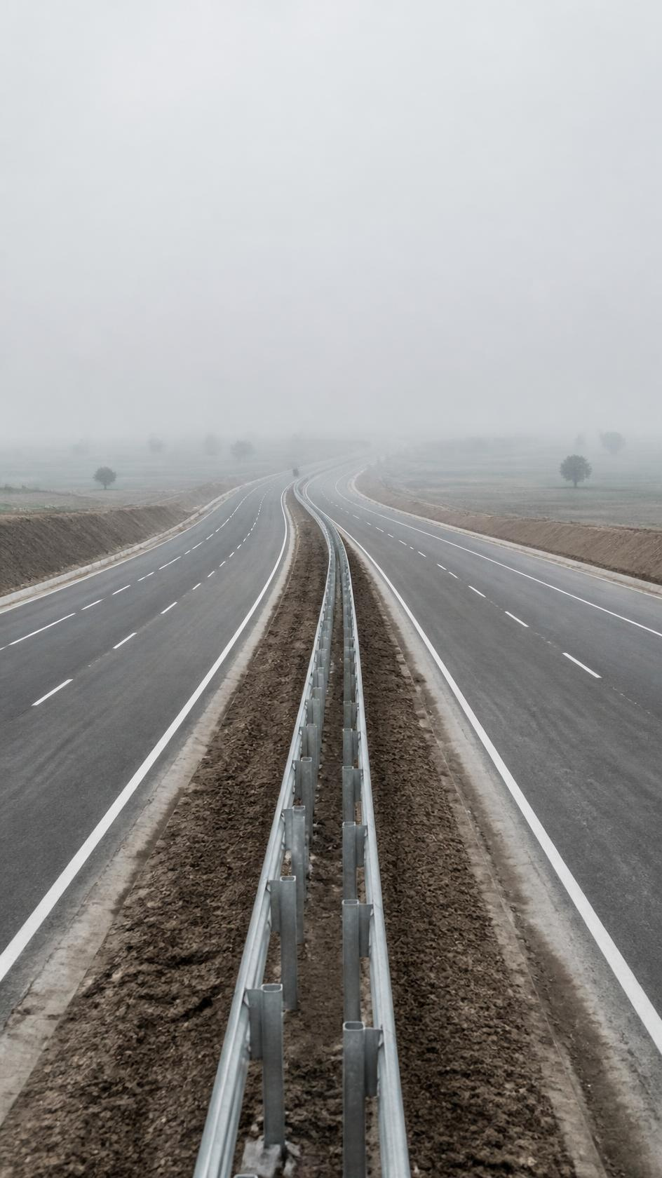 Empty newly completed four-lane divided carriageway with paved shoulders